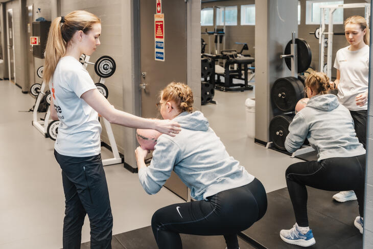 Dame trener knebøy med instruktør Dame trener knebøy med instruktør
